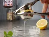A hand is using a manual juicer to squeeze lemon juice into a bowl. A halved lemon is visible in the background. Produktbild-Vorschau