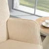 A close-up view of a beige corduroy armchair next to a round wooden table with a teacup on it, with a window and greenery in the background. Produktbild-Vorschau