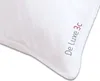A close-up view of a white pillow with text printed on the corner. Náhled obrázku produktu