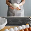 A person is holding dough over a baking mat with eggs and a bowl nearby. Voir les images du produit