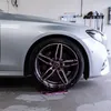 A silver car's wheel is being cleaned with a purple cleaning solution that is dripping onto the floor. Produktbild-Vorschau