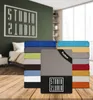 A bedroom scene with a wall graphic and stacks of folded bedding in various colors. Produktbild-Vorschau