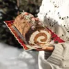 A person holding a Christmas log cake on a festive plate. Produktbild-Vorschau