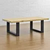 A wooden coffee table with black metal legs is shown against a white brick wall and a wooden floor. Anteprima dell’immagine prodotto