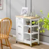 A kitchen cart with drawers and shelves is shown in a dining room setting next to a chair. Náhľad obrázku produktu