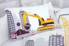 A close-up view of a pillow with a construction site design, featuring an excavator, buildings, and traffic signs. Produktbild-Vorschau