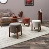 A living room scene with a chair, coffee table, and three ottomans on a rug. Voir les images du produit
