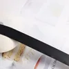 A black ribbon is laid across a white surface with a roll of white ribbon and a slice of cake in the background. Produktbild-Vorschau