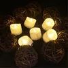 A group of LED tea lights are arranged around decorative rattan balls on a dark background. Produktbild-Vorschau