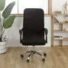 A black office chair with a cover on it, placed in a room with a plant and a shelf. Voir les images du produit