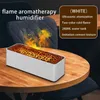 A white aromatherapy humidifier with a flame effect sits on a wooden table, with chairs in the background. Náhled obrázku produktu