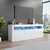 A modern living room with a TV mounted on a gray wall above a white TV stand with LED lighting. A large window shows a city skyline and trees. Produktbild-Vorschau