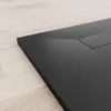 A close-up, angled view of a black shower tray on a light wooden floor. Produktbild-Vorschau