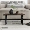A coffee table with a vase and a mug on it, placed on a rug in front of a sofa. Náhľad obrázku produktu