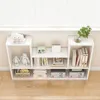 A white modular bookshelf unit filled with decorative items and books, placed against a light-colored wall and in front of a window with blinds. Náhľad obrázku produktu