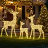 Three illuminated reindeer figures are displayed on a lawn in front of a house decorated for Christmas. Produktbild-Vorschau