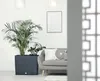 A modern living room with a large planter, a sofa with decorative pillows, and a framed picture on the wall. Náhled obrázku produktu