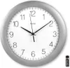 A wall clock with a silver frame and a white face, showing the time. A battery is placed next to the clock. Anteprima dell’immagine prodotto