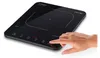 A hand pressing a button on a black induction cooktop. Produktbild-Vorschau