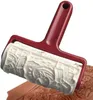 A baking roller with a red handle and a white patterned roller is shown pressing a pattern into a brown dough. Produktbild-Vorschau