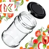 A clear glass jar with a black lid, surrounded by fresh vegetables and herbs. Anteprima dell’immagine prodotto