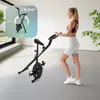 A woman is using a foldable exercise bike in a bright, modern room. Anteprima dell’immagine prodotto