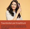 A woman is using a rose gold automatic hair curler on her dark hair against a light orange background. The bottom of the image has a dark red overlay with German text describing the product. Náhled obrázku produktu