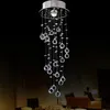A crystal chandelier hanging in a dark room, with a hint of furniture and a table setting in the background. Produktbild-Vorschau