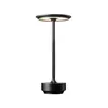 A black LED table lamp with a circular shade and a cylindrical base, shown against a white background. Produktbild-Vorschau
