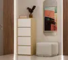 A narrow chest of drawers next to a wall with a mirror and a pouf. Voir les images du produit