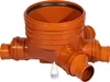 An orange plastic sewage pipe fitting with multiple inlets and outlets, shown on a white background. A small white bottle of lubricant is placed in front of the fitting. Produktbild-Vorschau