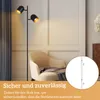 A floor lamp with two adjustable heads is shown in a living room setting next to an armchair. A circular inset shows a diagram of a pole with connection points. Produktbild-Vorschau