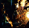 Several wine glasses are lined up on a textured surface, with flames engulfing the tops of some of them. Anteprima dell’immagine prodotto
