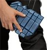 A hand is holding a blue knee pad over black pants. Produktbild-Vorschau