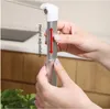 Hands adjusting the height of a silver pole, with a red arrow indicating the adjustable direction. Produktbild-Vorschau