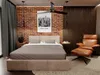 A bedroom with a bed, chair, and wall decor. Produktbild-Vorschau