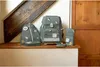 A collection of green school bags and accessories are displayed on a wooden shelf. Voir les images du produit