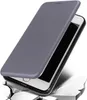 A gray flip case for a smartphone is shown open, revealing the phone's screen and frame. The case is angled, and the phone appears to be falling or being dropped, with abstract representations of breaking ground beneath it. Produktbild-Vorschau