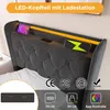 A close-up view of a gray upholstered headboard with integrated LED lighting and charging ports. Produktbild-Vorschau