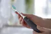 A person's hands holding an electric toothbrush. Produktbild-Vorschau