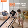 Two young men playing shuffleboard in a living room. Náhľad obrázku produktu