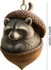 A decorative ornament of a raccoon sleeping inside an acorn. Produktbild-Vorschau