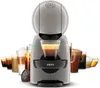 A gray Krups Dolce Gusto coffee machine is shown in the center, with various coffee drinks displayed in glasses and cups behind it. Náhled obrázku produktu