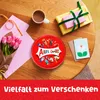 A table setting with a gift box, a cup of coffee, a bouquet of tulips, a tin of chocolates, and a greeting card. Produktbild-Vorschau
