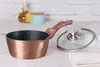 A rose gold saucepan with a glass lid is displayed on a white surface, with a bottle of oil and a blue container in the background. Náhled obrázku produktu