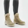 A person wearing dark gray jeans and beige winter boots. Voir les images du produit