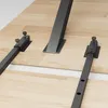 Close-up view of metal table extension rails and a table leg on a wooden surface. Produktbild-Vorschau