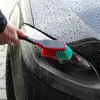 A hand is using a car wash brush to clean a car headlight. Produktbild-Vorschau