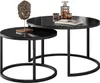 A set of two nesting coffee tables with black glass tops and black metal frames. A decorative lion head sculpture and some glassware are on the larger table. Náhľad obrázku produktu