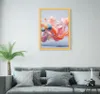 A framed abstract artwork is displayed on a wall above a gray sofa with several pillows. A potted palm tree is to the left of the sofa, and a small black side table with a diffuser is to the right. Produktbild-Vorschau
